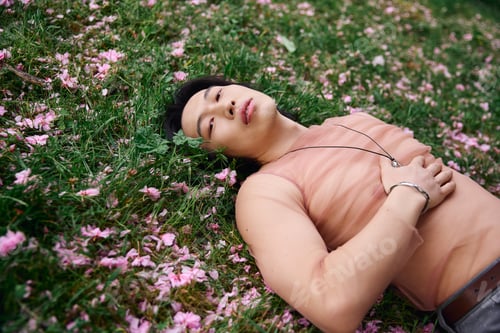 Preview: Young asian man expresses style and tranquility in a park adorned with blooming flowers