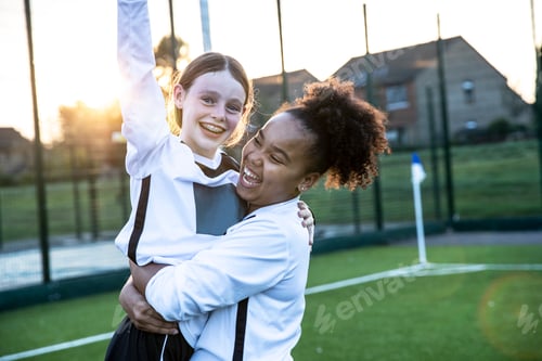 Preview: Joyful teammates celebrating a goal at sunset on the soccer field.