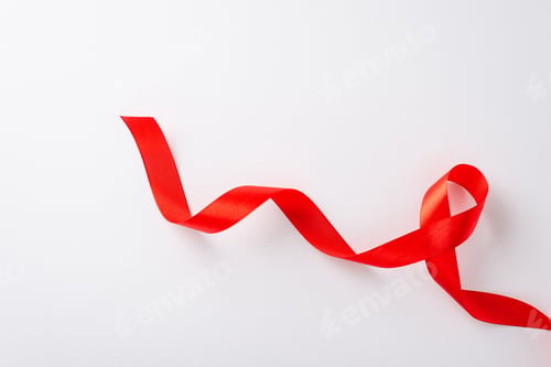 Preview: HIV Awareness Month idea: Top view of a red ribbon on a blank