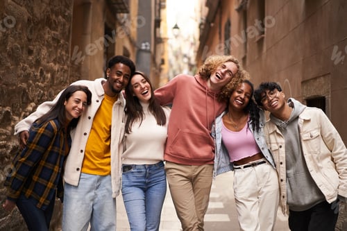 Preview: Group of twenties people looking at the camera in the street. Happy smiling friends hugging