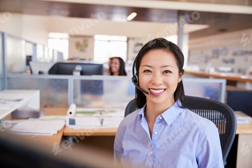 Preview: Young Asian woman working in a call centre smiling to camera