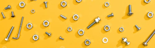 Preview: Top view of metal nuts and bolts on yellow background, panoramic shot