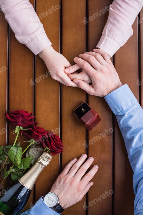 Preview: cropped image of boyfriend proposing girlfriend and holding her hand