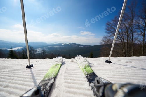 Preview: Skier legs in white snow, beautiful winter mountain landscape and blue sky copy space background.