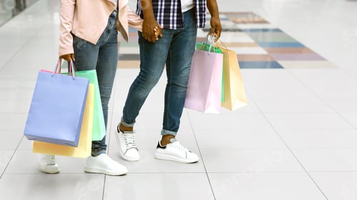 Preview: Unrecognizable African Couple Walking In Mall, Carrying Bright Shopping Bags, Cropped Image
