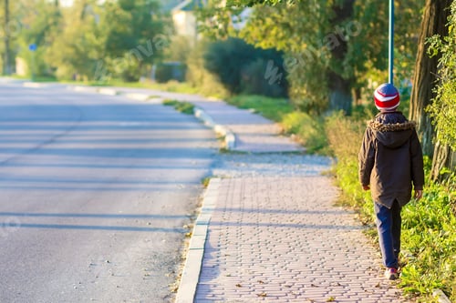 Preview: Child boy walking alone on a sidewalk