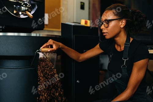 Preview: Young entrepreneur working in coffee production. Coffee beans exiting from a roasting machine.