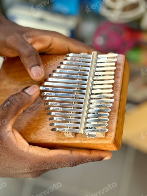 Preview: An unrecognizable diverse male musician plays a small African thumb drum kalimba by hand
