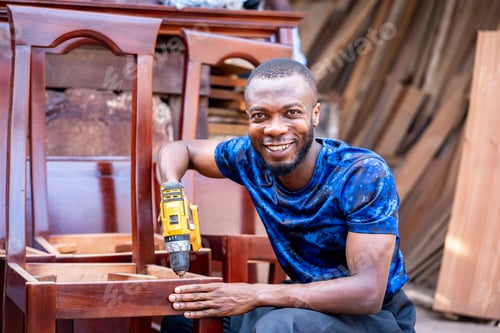 Preview: Cheerful African man with a drilling machine working in a workshop.