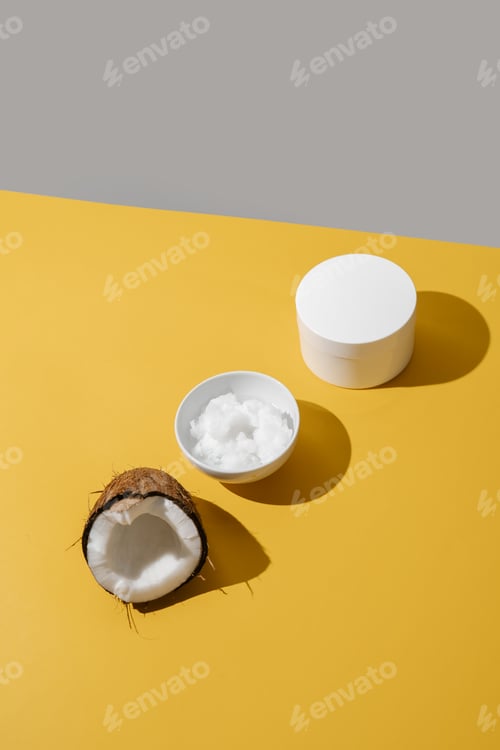 Preview: Half a coconut, coconut oil and a jar of coconut cream on a yellow background