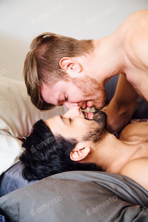 Preview: Male couple, bare chested, lying on bed, kissing