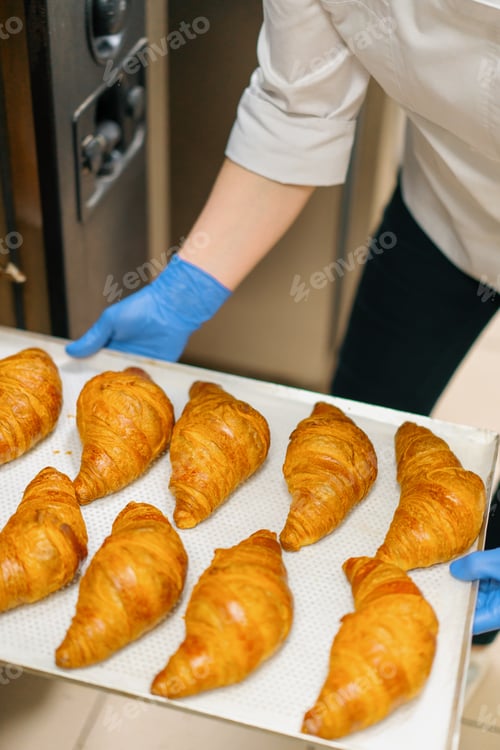 Preview: Kitchen in the bakery - ready-made croissants are taken from oven