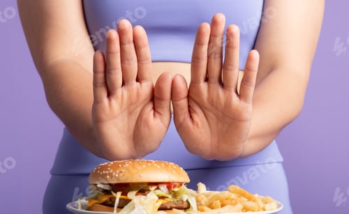 Preview: Sporty lady refuses burger and fries with stop gesture, purple studio, closeup