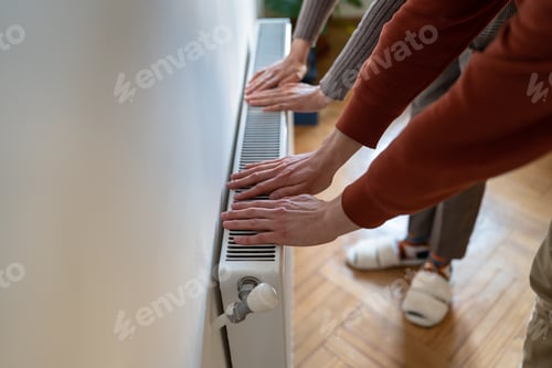 Preview: Hands suffer from lack of heat from high price on gas checking temperature heating radiator at home.