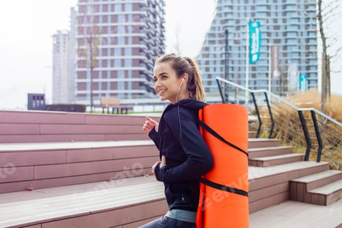 Preview: Fitness woman walking with mat on back outdoor