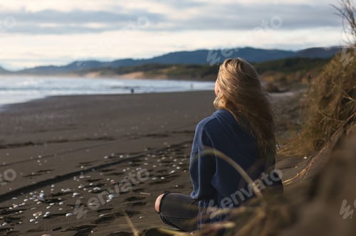 Preview: Young woman sits on the shore at sunset, gazing out into the glimmering sea