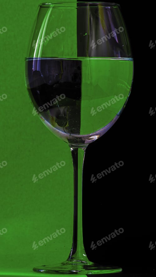 Preview: Vertical shot of a glass of water on a green and black background
