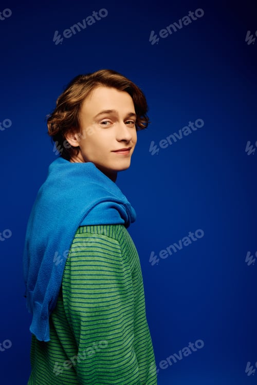 Preview: A confident young man in trendy attire poses with a relaxed demeanor, exuding youthful charm