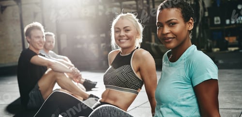 Preview: Two smiling young women sitting together on a gym floor