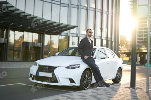 Preview: A successful man is staying leaning on his car in the street