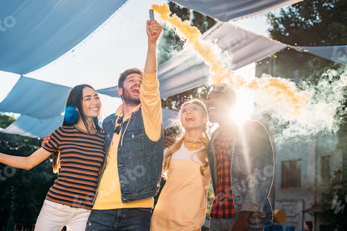 Preview: Interracial Cheerful Young Friends With Colorful Smoke Bomb in Park