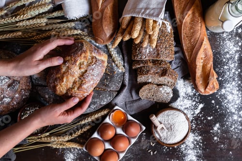 Preview: Young woman holding freshly baked dark round bread in her hands.