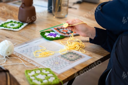 Preview: Person crocheting colorful granny squares following a pattern