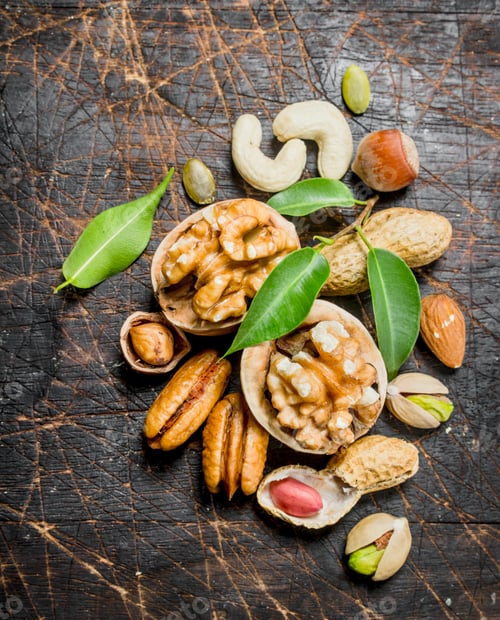 Preview: Nuts background. Assortment of different nuts with green leaves .