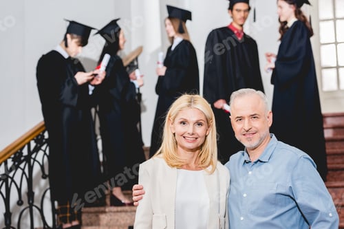 Preview: selective focus of happy parents looking at camera near students