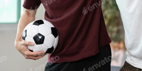 Preview: Adult Holds Soccer Ball with Teammate Nearby