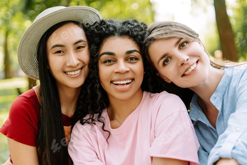 Preview: Portrait of young, multinational women smiling and having fun together outdoors, looking at camera