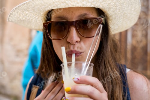 Preview: Smiling woman with frozen drink walking through historic town