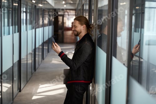 Preview: Stylish man browsing cell phone in hallway