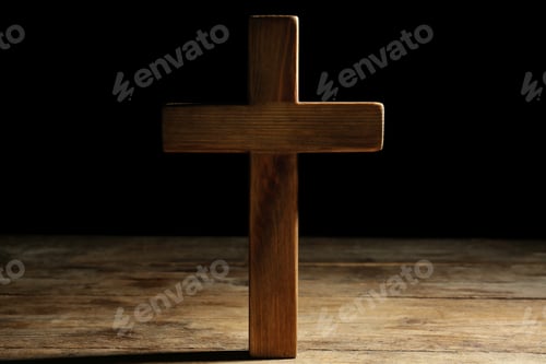 Preview: Christian cross on wooden table against black background. Religion concept