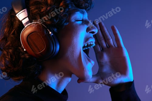 Preview: Male singer wearing headphones listening to music and singing with his mouth open, sound recording