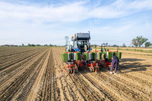 Preview: Farmer working in a large agricultural field with modern tractor