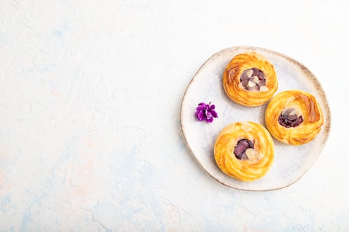 Preview: Small cheesecakes with jam and almonds with cup of coffee on a white concrete background