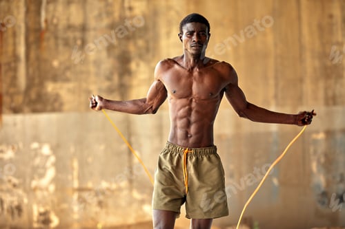 Preview: Muscular black man skipping rope. Portrait of muscular young man exercising with jumping rope