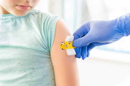 Preview: Vaccination of little girl in doctor's office.Kids funny adhesive plaster,gauze napkin.Hand in glove