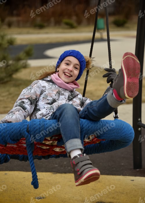 Preview: A girl in a blue hat rides a swing. Autumn. Childhood.