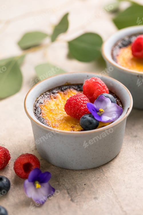 Preview: Creme brulee. French vanilla cream dessert with caramelised sugar and berries, selective focus.