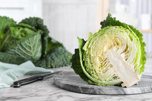 Preview: Half of fresh green savoy cabbage on white marble table