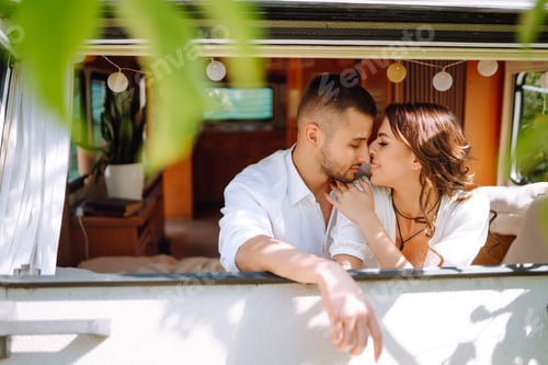 Preview: Beautiful wedding couple laugh and kiss relaxing in rv, camping in a trailer. Romantic moment.