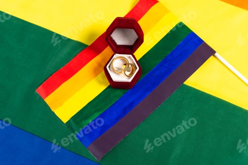 Preview: top view of wedding rings and lgbt flag on rainbow colors background