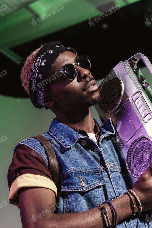 Preview: stylish young handsome african american man in sunglasses holding silver tape recorder