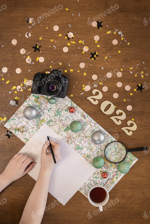 Preview: Christmas travel flat lay with numbers 2022, map, camera and white sheet.
