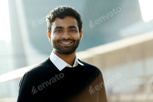 Preview: Handsome smiling Indian man looking at camera standing on the street