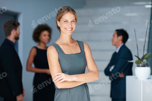 Preview: Portrait of a young businesswoman standing in an office with colleagues in the background