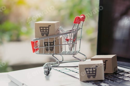 Preview: Shopping online. Cardboard box with a shopping cart logo in a trolley on laptop keyboard.