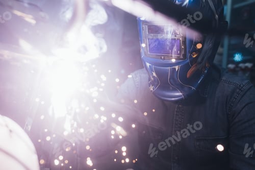 Preview: Mature man in garage, working on motorcycle, using welding equipment